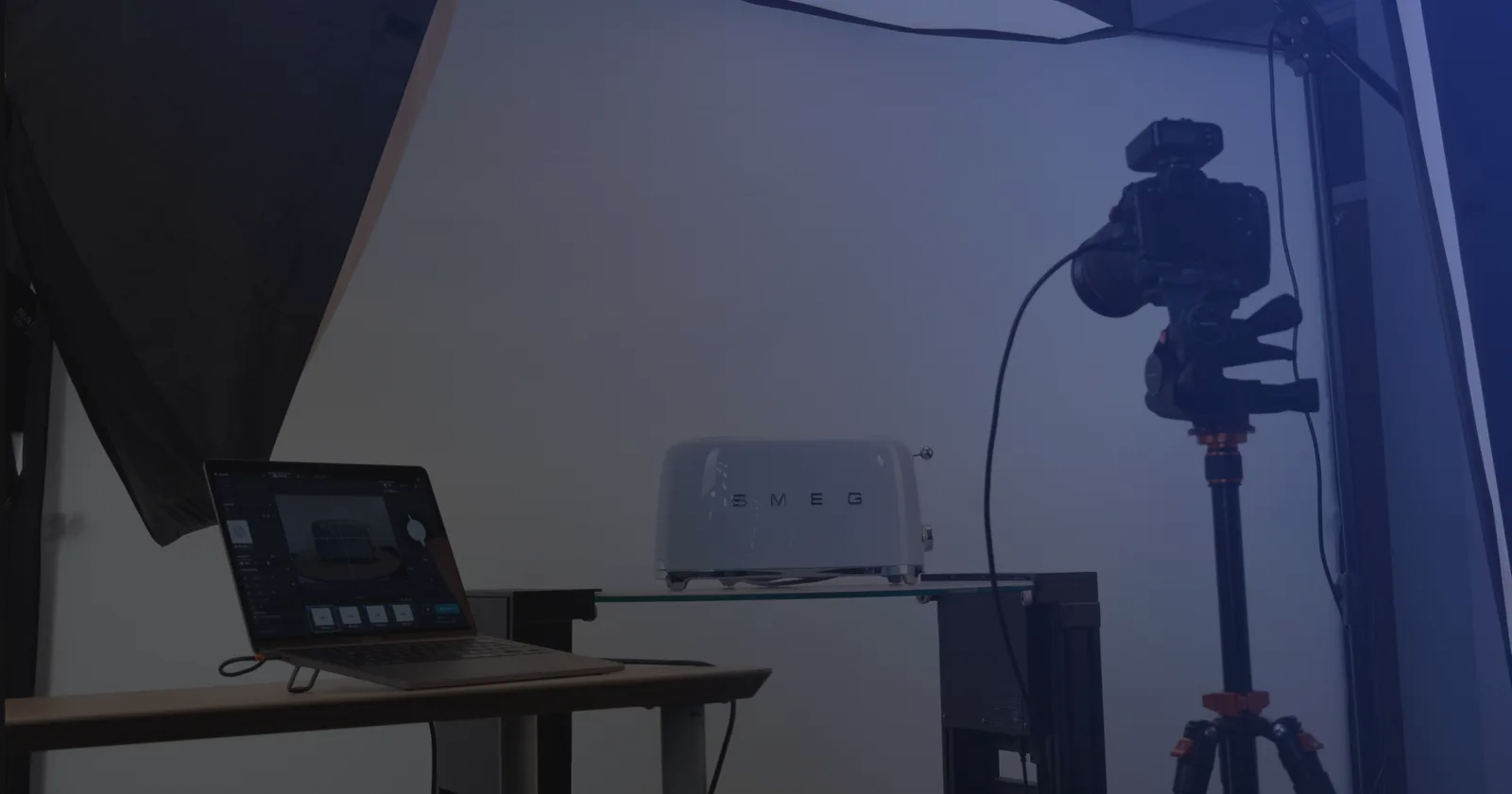 Set de fotografía de producto con tethering: un portátil con el software de captura junto a una cámara en trípode y un producto sobre una balda de cristal