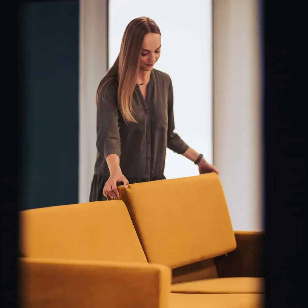 Mujer colocando cojines en un sofá amarillo para una sesión de fotos